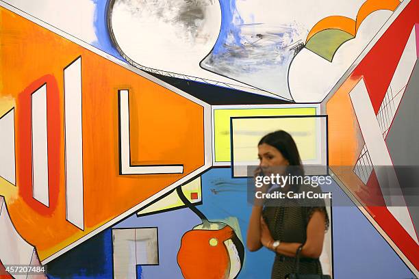 Woman talks on her phone next to a paintings by artist Thomas Scheibitz entitled 'Studio' during the VIP and press day at the Frieze Art Fesival on...