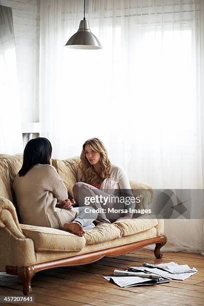 female flatmates relaxing on sofa - amigos charlando fotografías e imágenes de stock