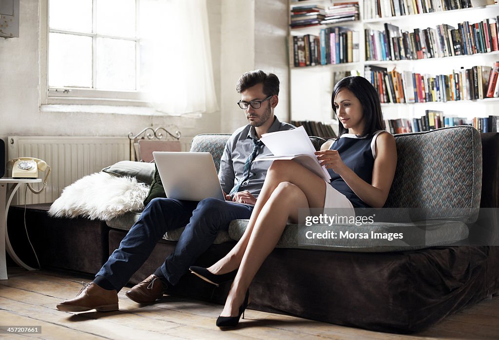 Couple sitting on sofa working