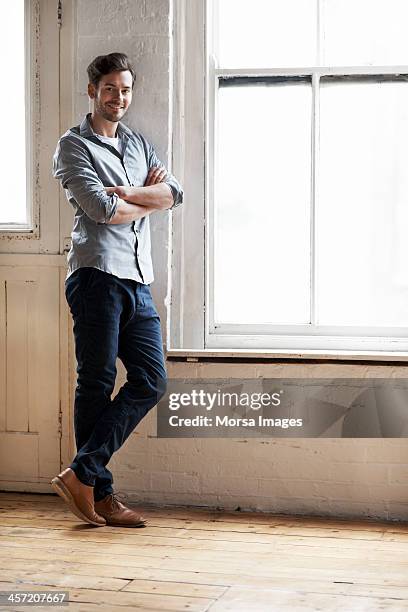 portrait of man standing by window - leaning stockfoto's en -beelden
