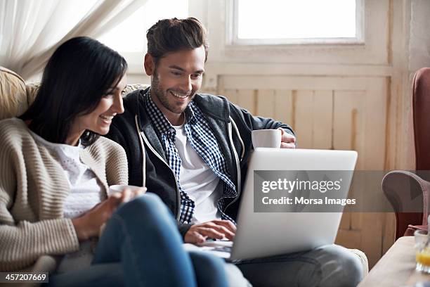 couple looking at laptop - couple couch imagens e fotografias de stock