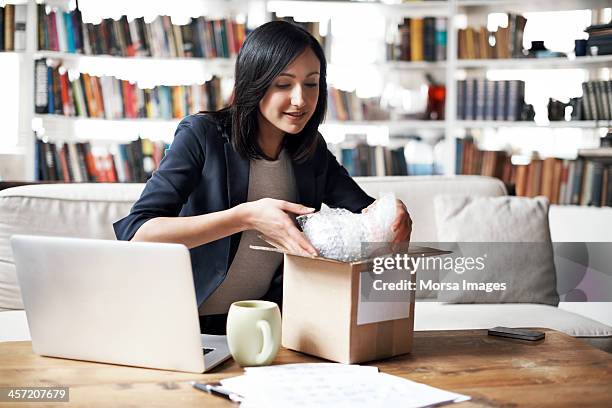 woman preparing parcel for shipment - debilidad fotografías e imágenes de stock