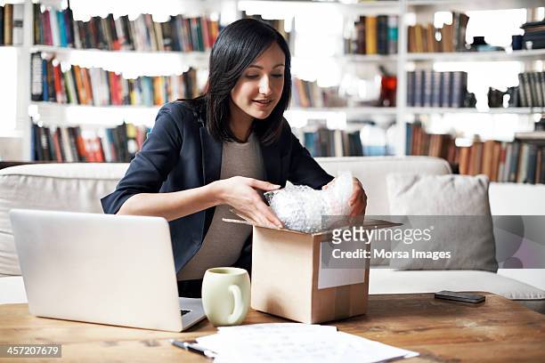 woman preparing parcel for shipment - versturen stockfoto's en -beelden