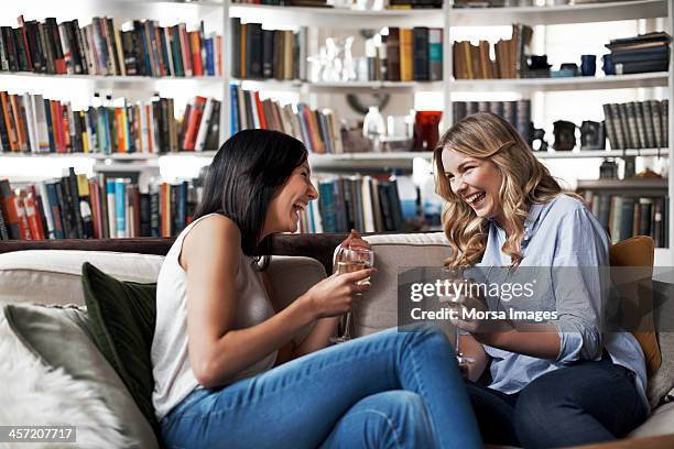 women sitting on sofa laughing - wein trinken stock-fotos und bilder