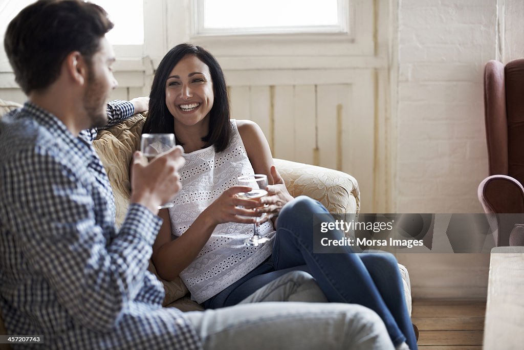 Couple sitting on sofa drinking wine