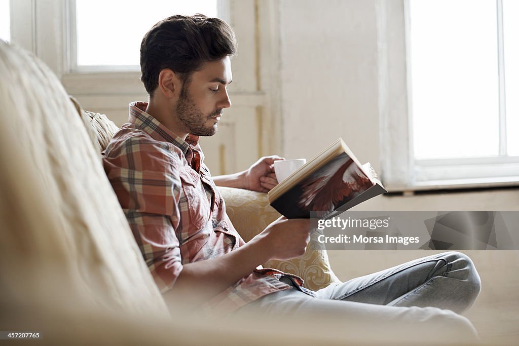 Man sitting on sofa reading book