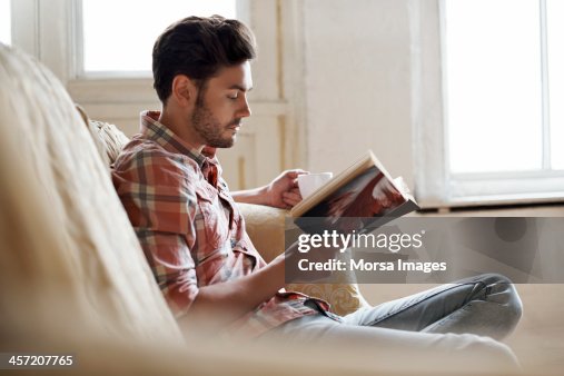 Man sitting on sofa reading book Man sitting on sofa reading book