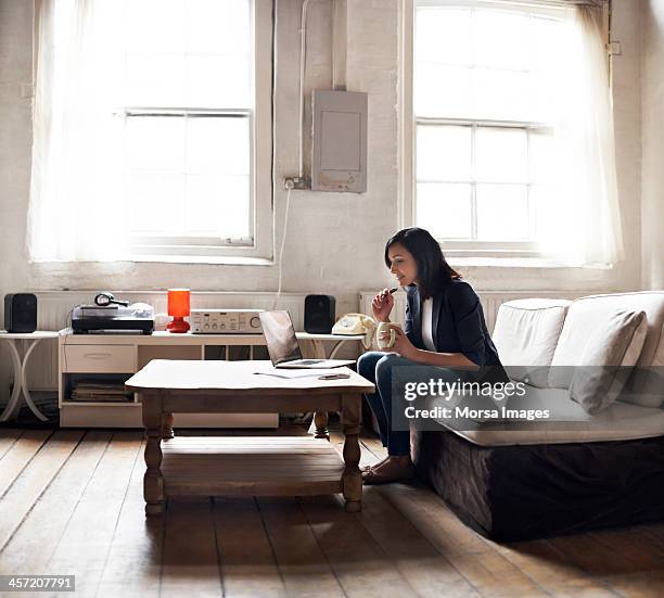 woman sitting on sofa using laptop - coffee table stock pictures, royalty-free photos & images