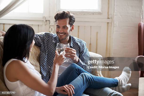 couple sitting on sofa talking and drinking wine - brown hair drink wine stock-fotos und bilder