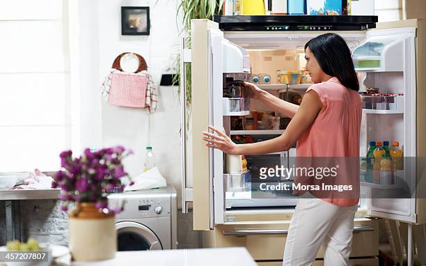 woman looking in the fridge - refrigerator stock-fotos und bilder