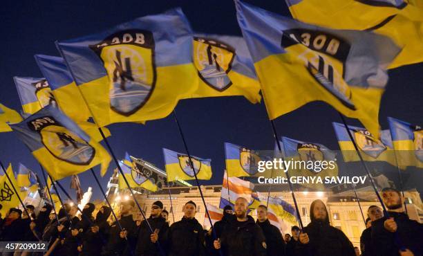 Ukrainian nationalists and servicemen of the Azov battalion wave flags in Kiev on October 14, 2014 during a march to mark the founding of the...