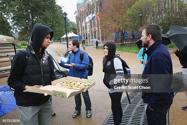 Saint Louis University student Jonathan Pulphus shares pizza sent by a professor to demonstrators at a small camp on the university campus on October...