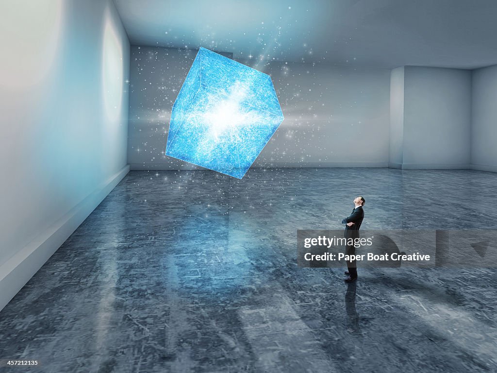 Man looking up at a glowing blue 3D cube