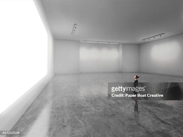 woman looking at giant glowing white screen - exhibition foto e immagini stock