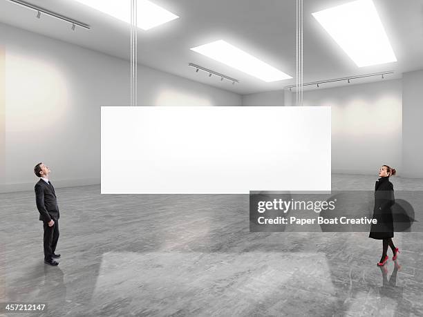 two business people looking at a large white sign - blank canvas stockfoto's en -beelden