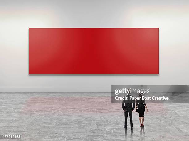 business people looking at giant red art canvas - man stand stockfoto's en -beelden