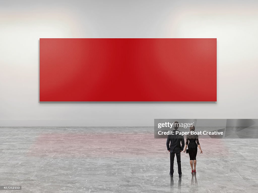 Business people looking at giant red art canvas