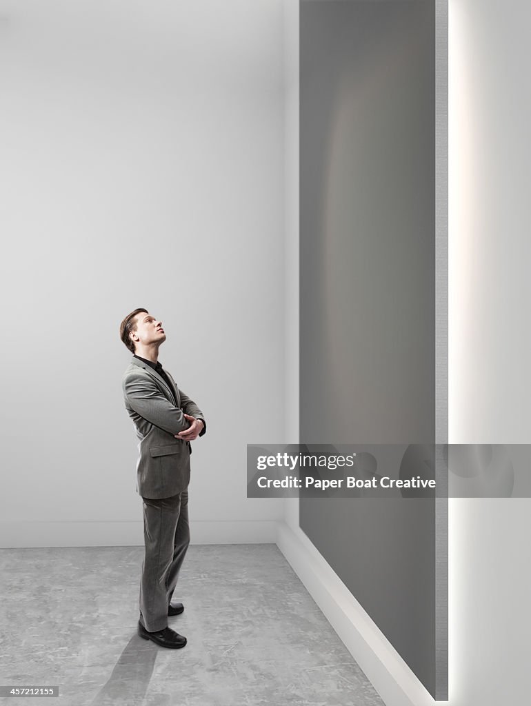 Business man looking up at blank grey canvas