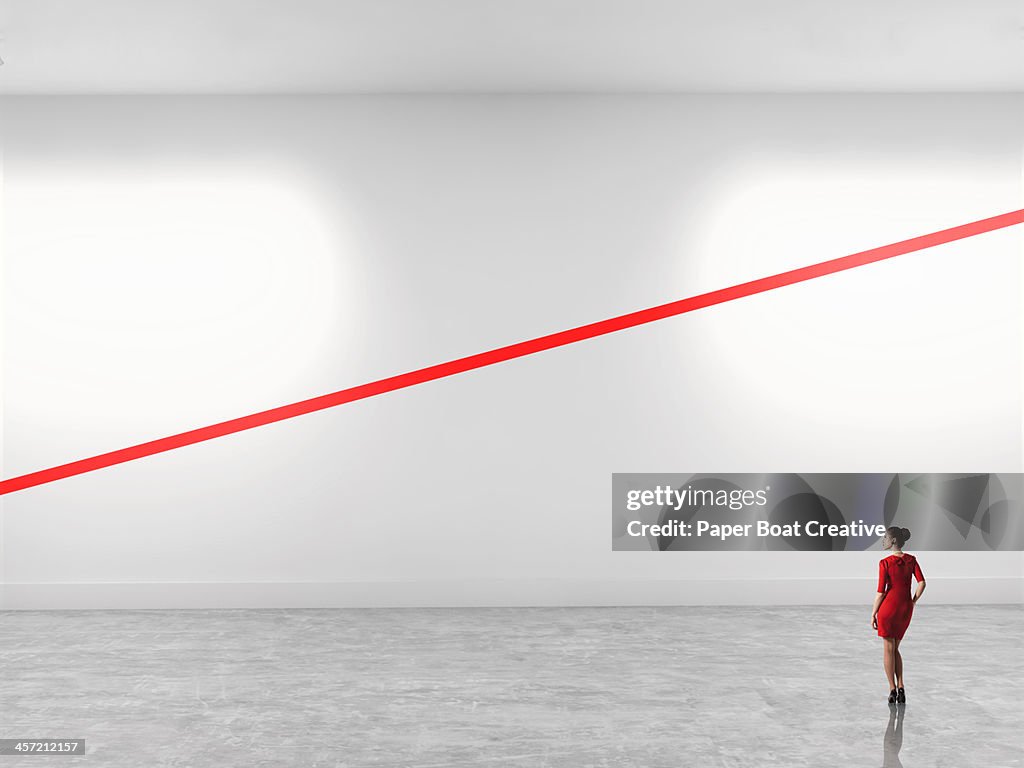 Woman looking at a diagonal red line in gallery