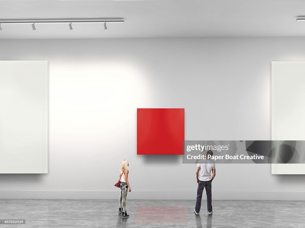 Couple looking at red blank art in gallery