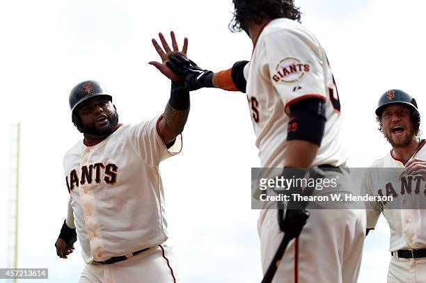 Pablo Sandoval, Brandon Crawford and Hunter Pence of the San Francisco Giants celebrate after Sandoval and Pence score in the first inning against...