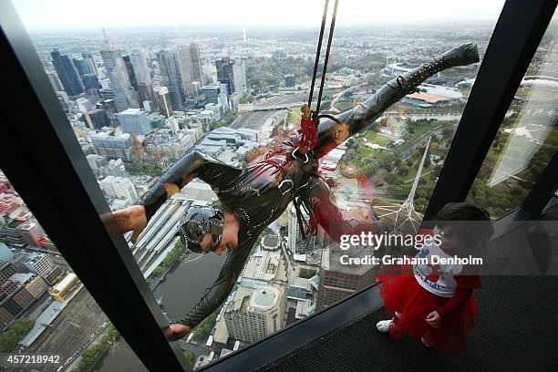 Stuntwoman Rowena Davies scales the outside of the Eureka Tower dressed as Catwoman as childhood heart disease sufferer Maisy Bodinnar looks on at...