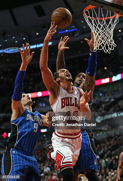 Joakim Noah of the Chicago Bulls puts up a shot between Nikola Vucevic and Glen Davis of the Orlando Magic at the United Center on December 16, 2013...