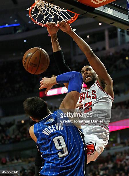 Taj Gibson of the Chicago Bulls dunks over Nikola Vucevic of the Orlando Magic at the United Center on December 16, 2013 in Chicago, Illinois. The...