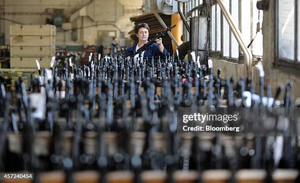 An employee holds a NATO standard M21 SBS assault rifle, manufactured by Zastava Arms, as firearms stand in racks on the production line at the...
