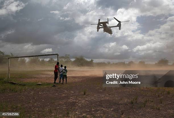 Boys watch as a U.S. Marine MV-22 Osprey tiltrotor departs the site of an Ebola treatment center under construction on October 15, 2014 in...