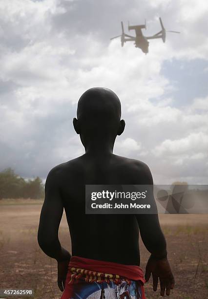 Boy watches as a U.S. Marine MV-22 Osprey tiltrotor departs the site of an Ebola treatment center under construction on October 15, 2014 in...