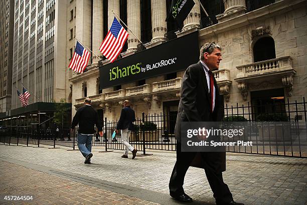 People walk along Wall Street past the New York Stock Exchange on October 15, 2014 in New York City. As fears from Ebola and a global slowdown...