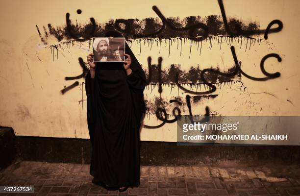 Bahraini women holds up a portrait of prominent Saudi Shiite cleric Nimr al-Nimr during clashes with riot police following a protest in solidarity...