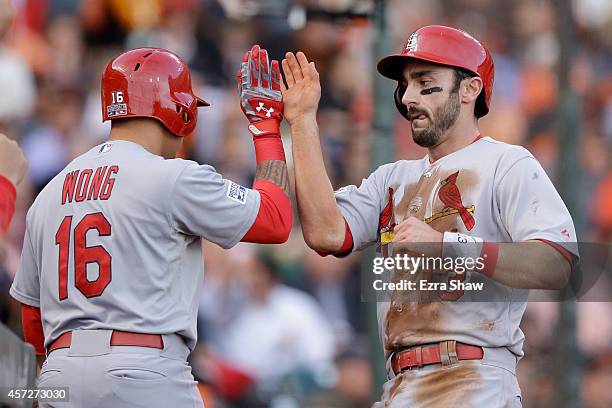 Matt Carpenter celebrates scoring in the first inning with teammate Kolten Wong of the St. Louis Cardinals against the San Francisco Giants during...