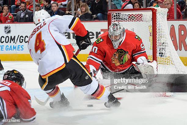 Kris Russell of the Calgary Flames attempts to put the puck past goalie Corey Crawford of the Chicago Blackhawks during the NHL game on October 15,...