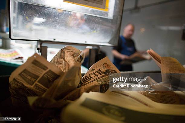 Discarded pages sit crumpled as employees inspect the print quality on copies of Vedomosti, a daily business newspaper owned by the Financial Times,...