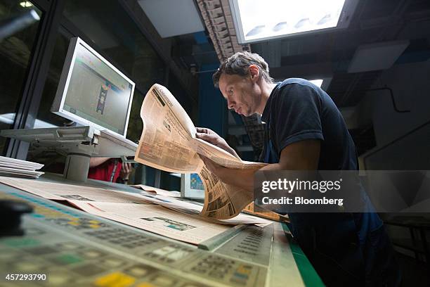 Employee inspects the page print quality on an edition of Vedomosti, a daily business newspaper owned by the Financial Times, the Wall Street Journal...