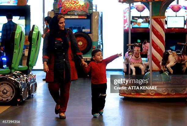 An Iranian woman walks with her child at the arcade in the Laleh Park shopping center in Tabriz in Iran's northwestern East-Azerbaijan province on...