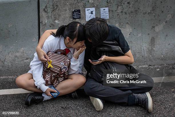 Students and pro-democracy activists watch a movie on a smartphone on the road outside Hong Kong's Government complex on October 16, 2014 in Hong...