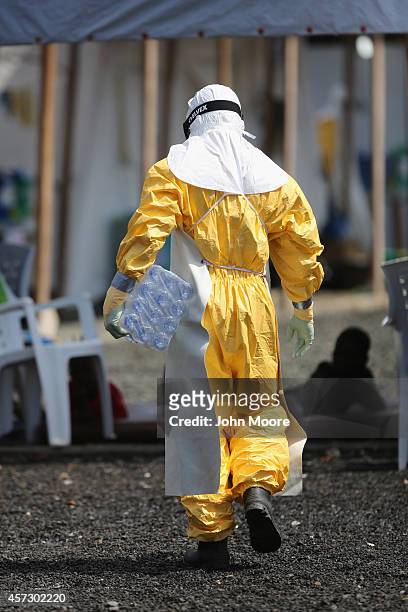 Health worker at Doctors Without Borders , carries bottled water through the high-risk area of the ELWA 3 Ebola treatment center on October 16, 2014...