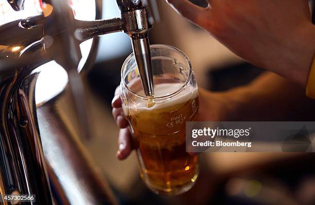 An employee pours a pint of Fosters lager, produced by Heineken NV, inside the Paul Pry pub, operated by John Barras, a unit of Spirit Pub Co., in...