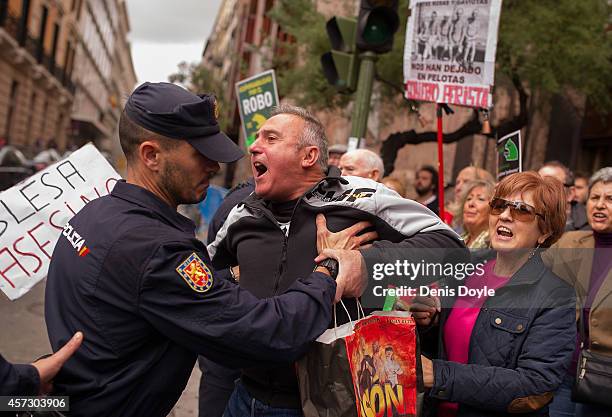 Protester is held back by a policeman at Madrid's High Court where Rodrigo Rato, former chairman of rescued bank Bankia and former head of the...