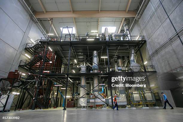 Employees pass a coffee bean roaster as it stands in a hall at the Nestle SA factory in Schwerin, Germany, on Thursday, Oct. 16, 2014. The factory,...