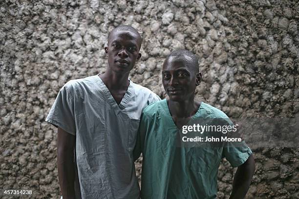 Ebola survivors Mark Jerry , and Zaizay Mulbah stand together before their shifts as nurse's assistants at the Doctors Without Borders , Ebola...