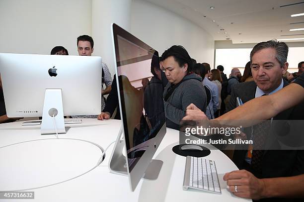 Attendees inspect the new 27 inch iMac with 5K Retina display during an Apple special event on October 16, 2014 in Cupertino, California. Apple...