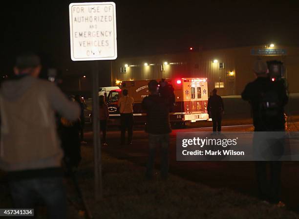 People watch as an ambulance carrying Texas Health Presbyterian Hospital nurse Nina Pham drives away from the Frederick Municipal Airport October 16,...