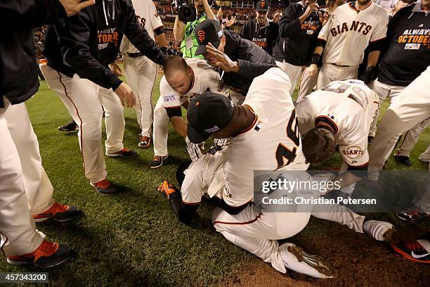 Travis Ishikawa of the San Francisco Giants is on the ground as he celebrates with his teammates after he hits a three-run walk-off home run to...