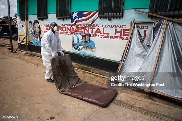 October 14: A nurse drags out a mattress coated with bodily fluids from inside the Island Clinic Ebola Treatment Unit on October 14, 2014 in...