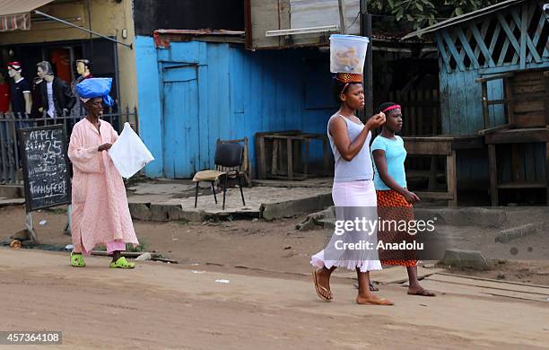 October 3 dated photo shows that a woman carries a bucket on her head in Abidjan, Ivory Coast, on October 3, 2014. Women living in Ivory coast work...