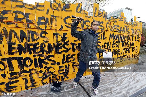 Graffiti artist Jonone gestures holding a text written by Abbe Pierre in front of a piece he realised using the same text in the gardens of the Abbe...